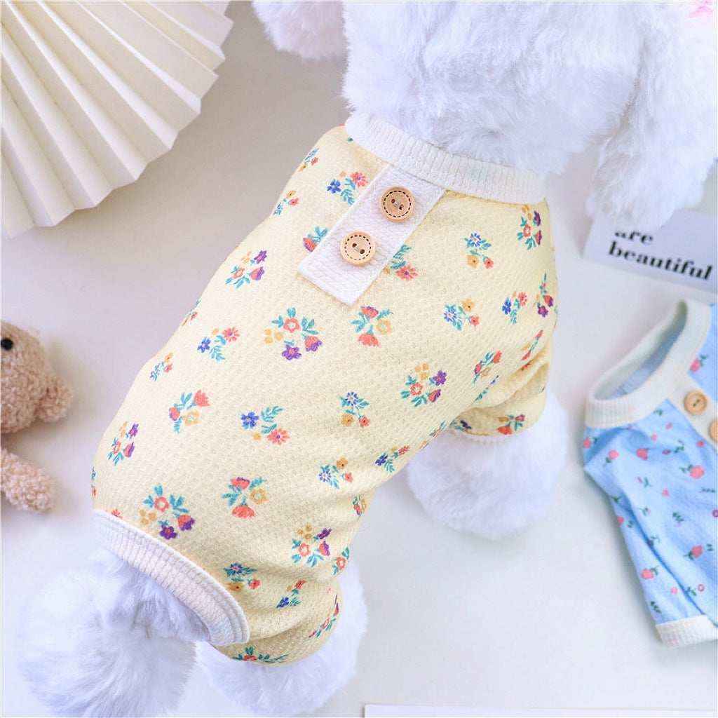 Small white dog wearing yellow floral pet clothes with two buttons on the collar