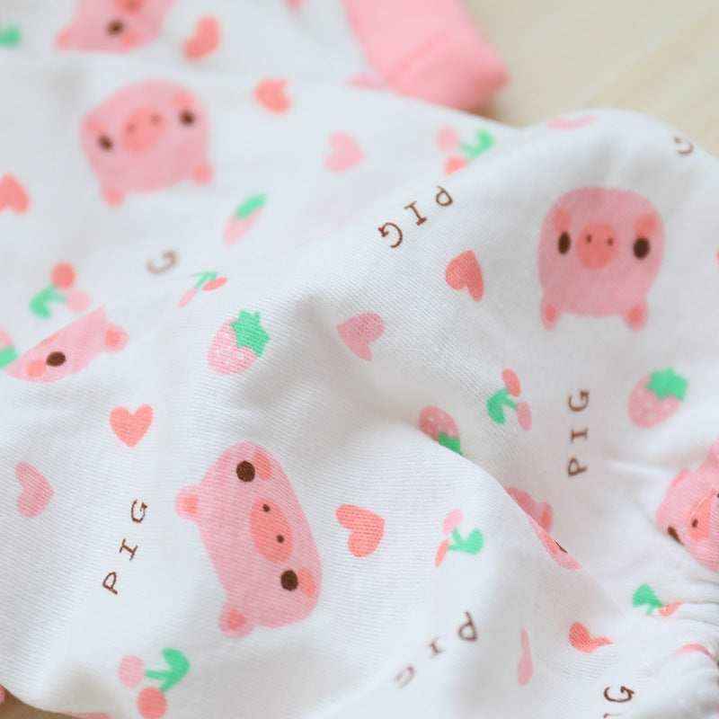 White fabric with cute pink pig faces, strawberries, and hearts pattern, soft textile close-up