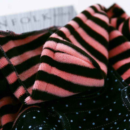Close-up of soft pink and black striped fabric on black textile with small white dots