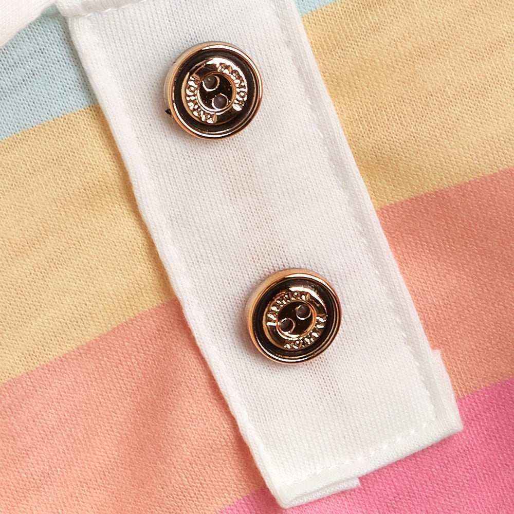 close-up of white fabric with two gold-tone snap buttons on pastel striped textile background