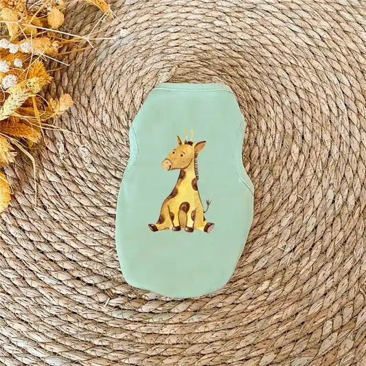 Light green baby bib with cute giraffe illustration placed on woven placemat with dried flowers