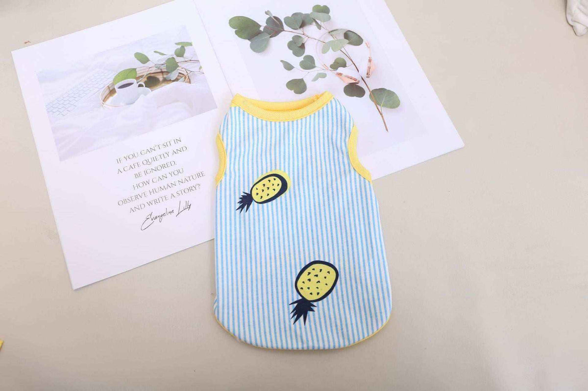 Small blue and white striped sleeveless pet shirt with yellow pineapples and trim on beige surface