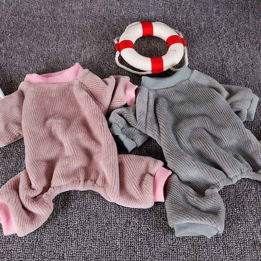 Two soft textured pet jumpers in pink and gray with ribbed cuffs on a gray carpet
