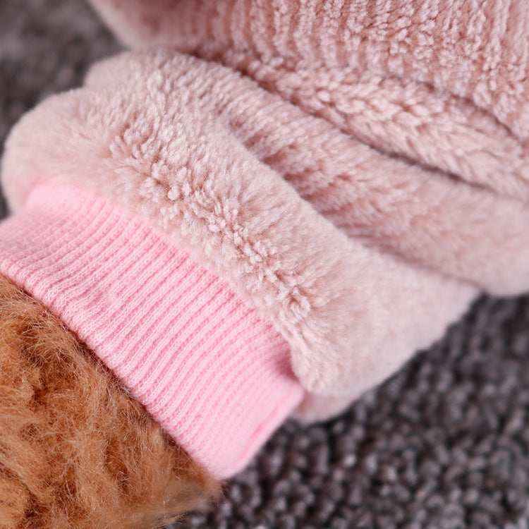 Close-up of soft pink fuzzy fabric with ribbed cuff and textured brown material on dark surface