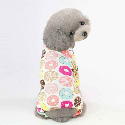 Small gray poodle wearing colorful donut print dog pajamas on white background