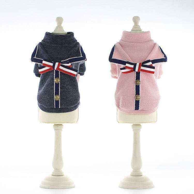 Two stylish dog sweaters on mannequins, one navy blue and one pink, each with a striped bow and decorative buttons