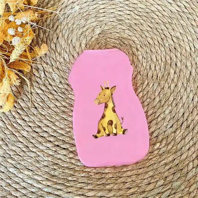 Pink pet shirt with cartoon giraffe design on round woven mat with dried flowers