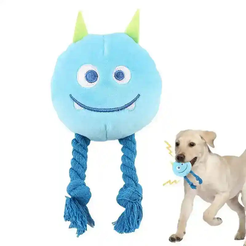 Blue plush monster dog toy with green horns and rope legs, held by playful yellow Labrador retriever
