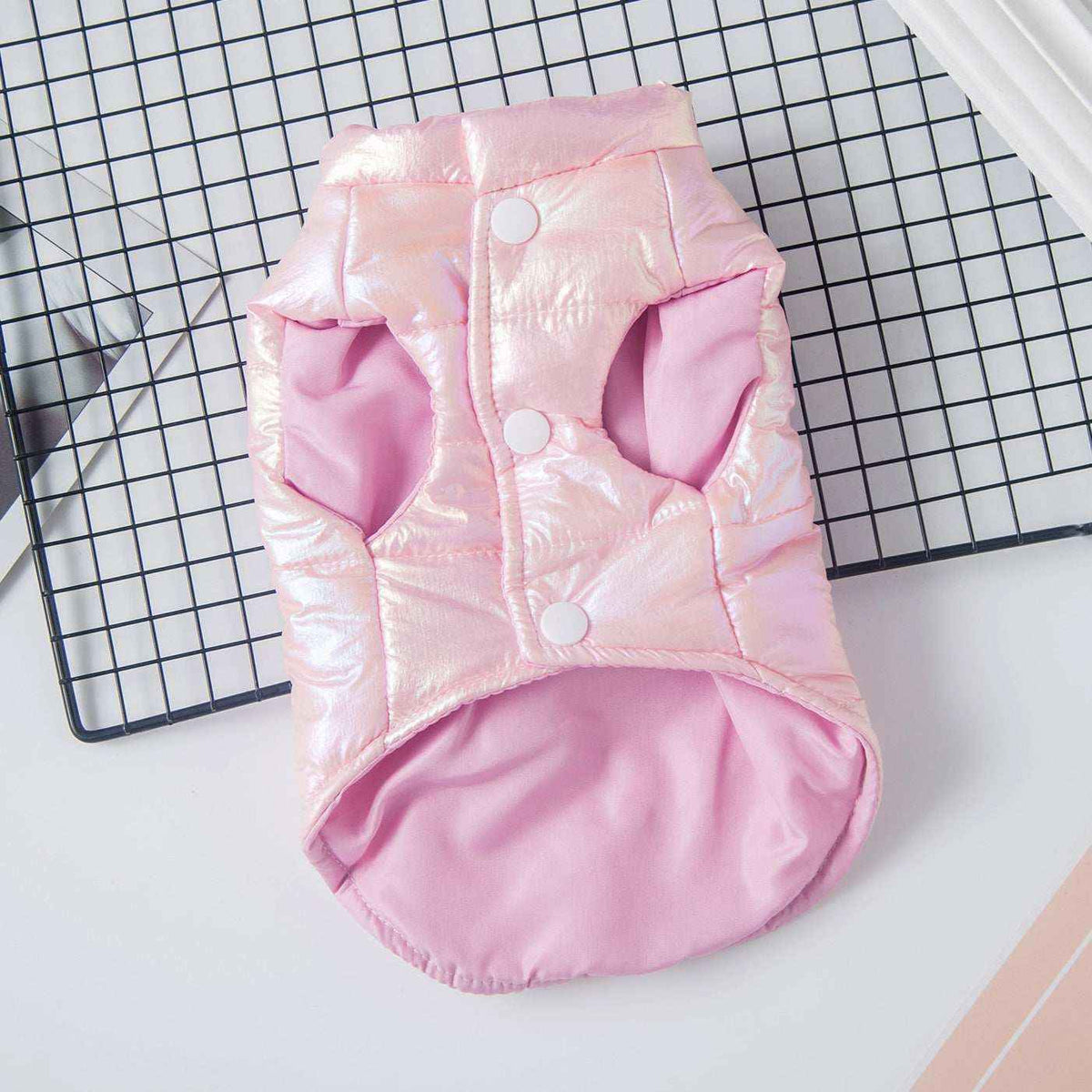 Pink iridescent pet jacket with snap buttons on black grid and white background