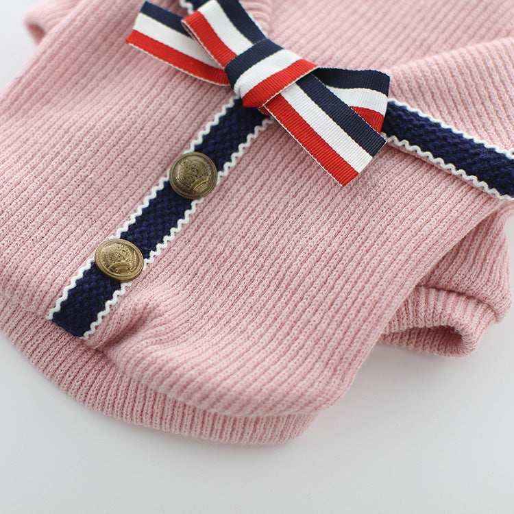 Pink knit sweater with navy blue and white trim, gold buttons, and red white blue ribbon bow