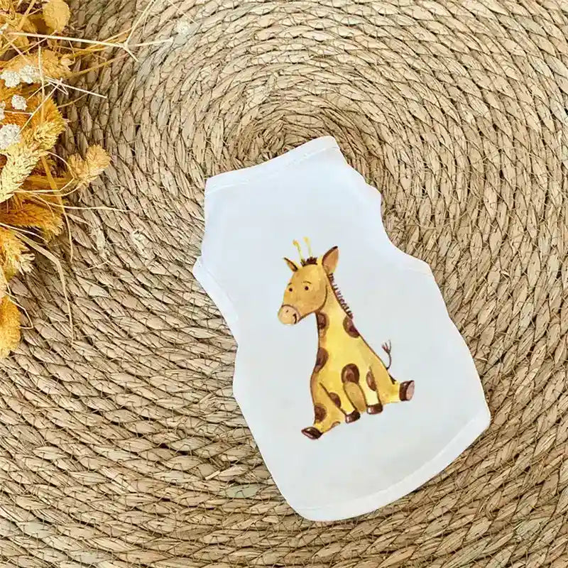 White pet shirt with cute giraffe illustration on woven rattan mat with dried flowers
