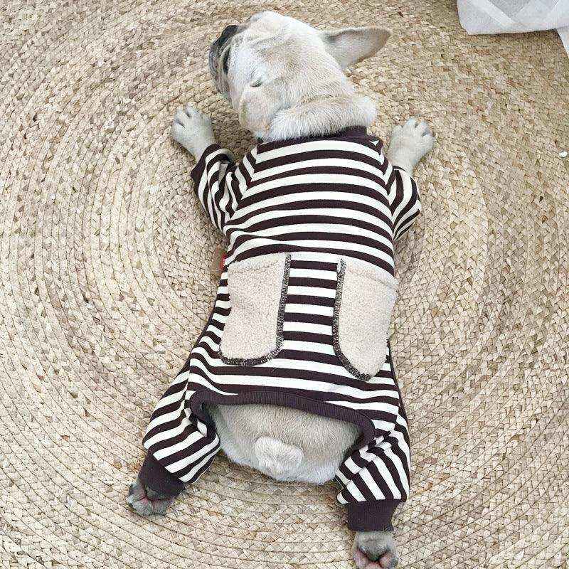 French bulldog puppy wearing striped pajamas with pockets lying on woven rug