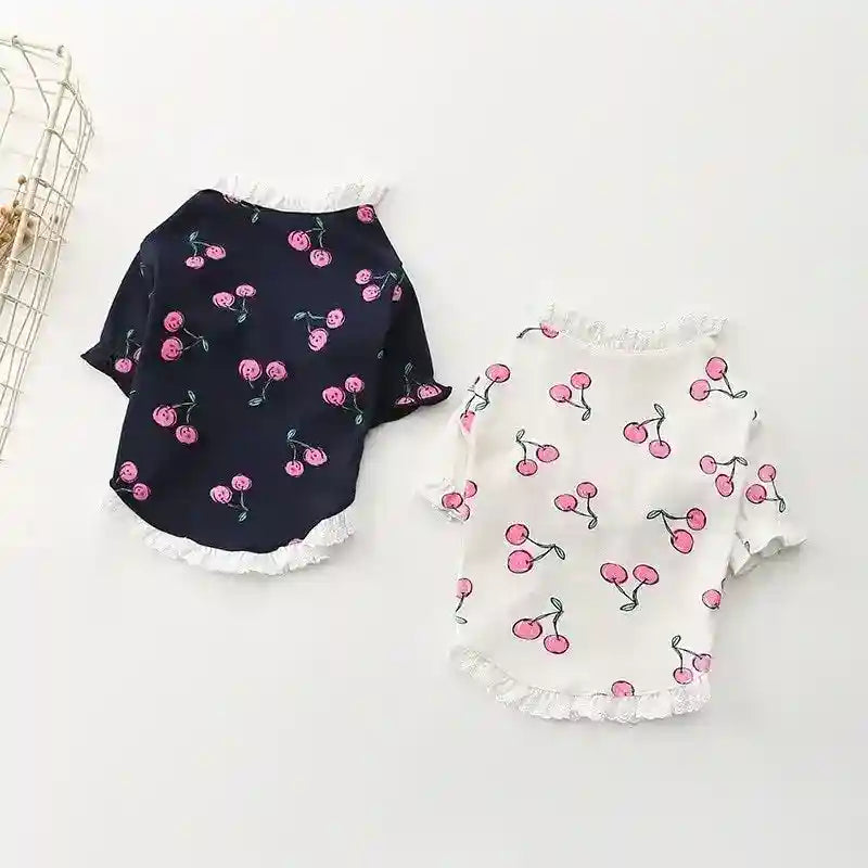 Two dog shirts with pink cherry patterns, one in navy blue and one in white, with lace trim