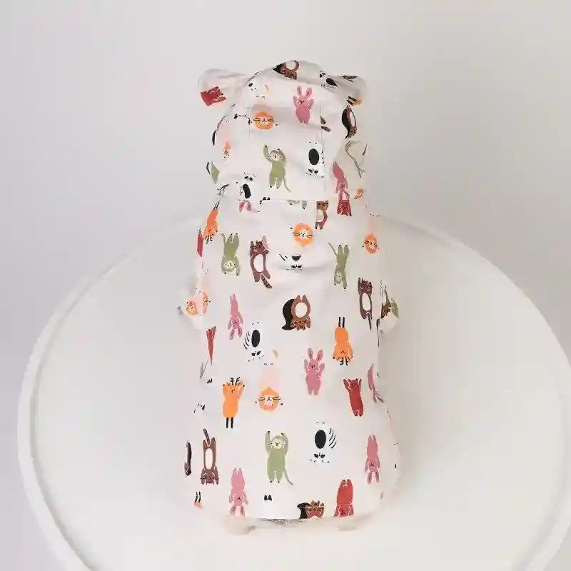 Small dog wearing white hoodie with colorful cartoon animal print and bear ears on hood