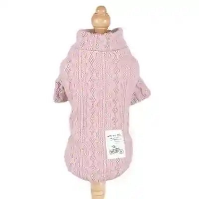 Pink cable knit dog sweater with turtleneck and white patch on back, displayed on wooden mannequin