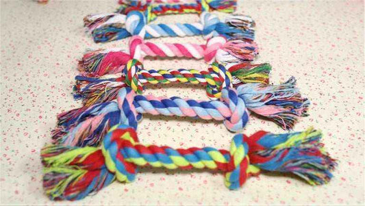 Colorful cotton rope dog chew toys in a row on a textured surface