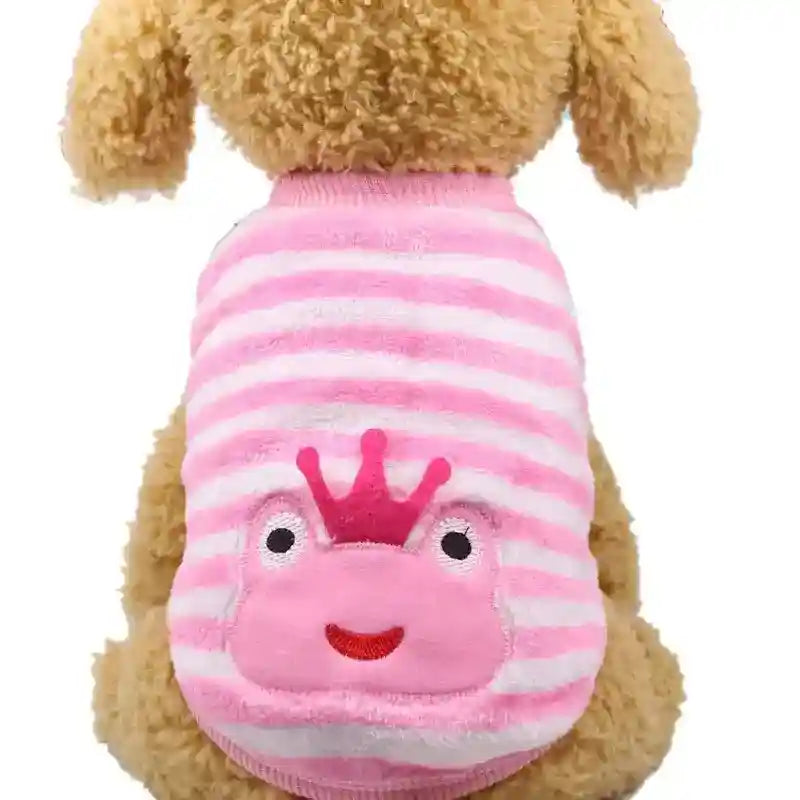 Small dog wearing a pink and white striped sweater with a smiling frog face and crown design