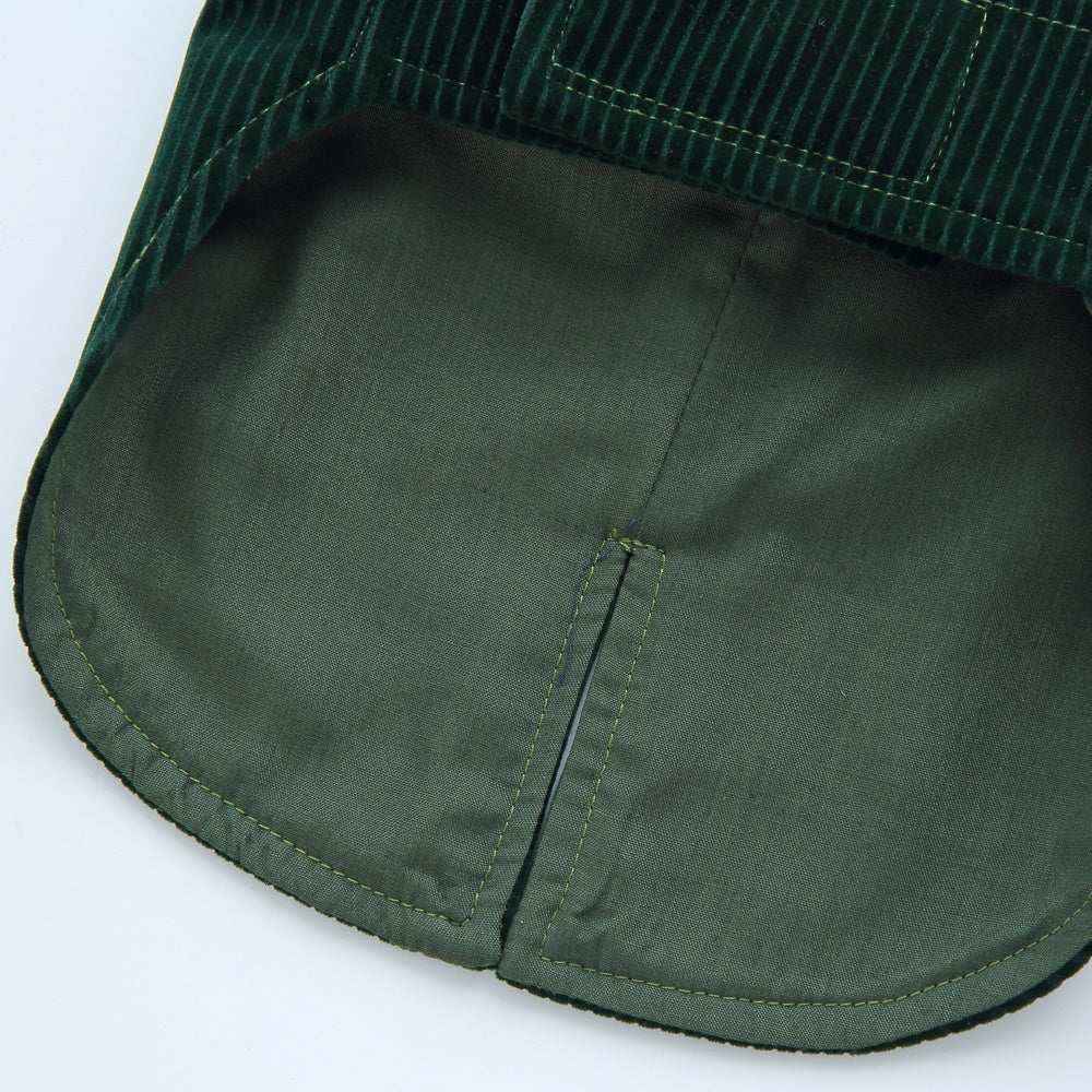 Close-up of green corduroy and smooth fabric jacket hem with split seam detail