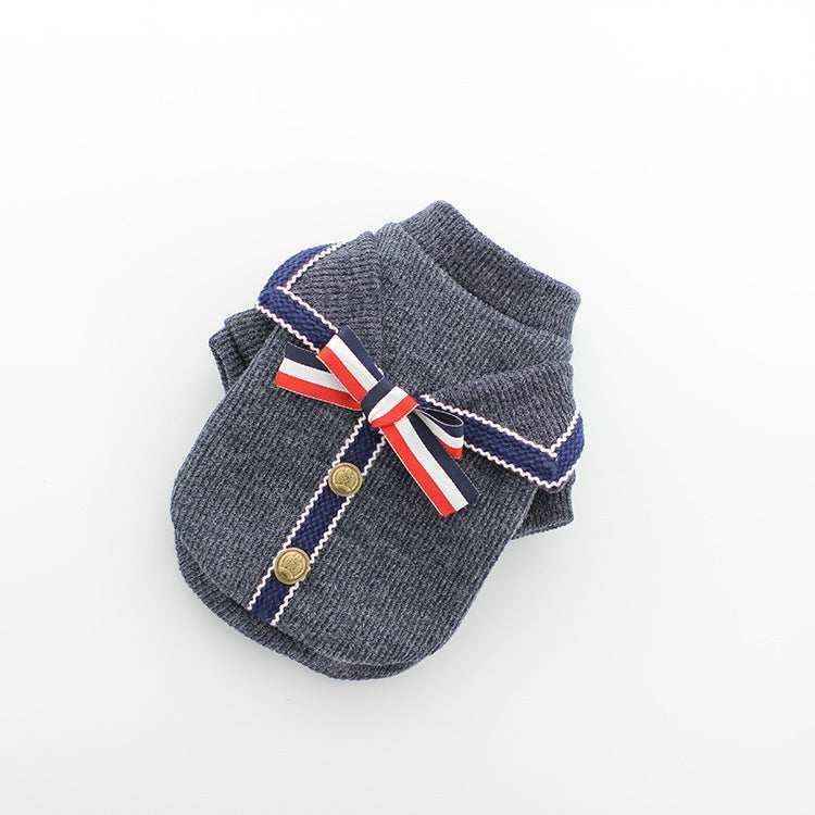 Gray knit dog sweater with navy trim, gold buttons, and a red white blue ribbon bow