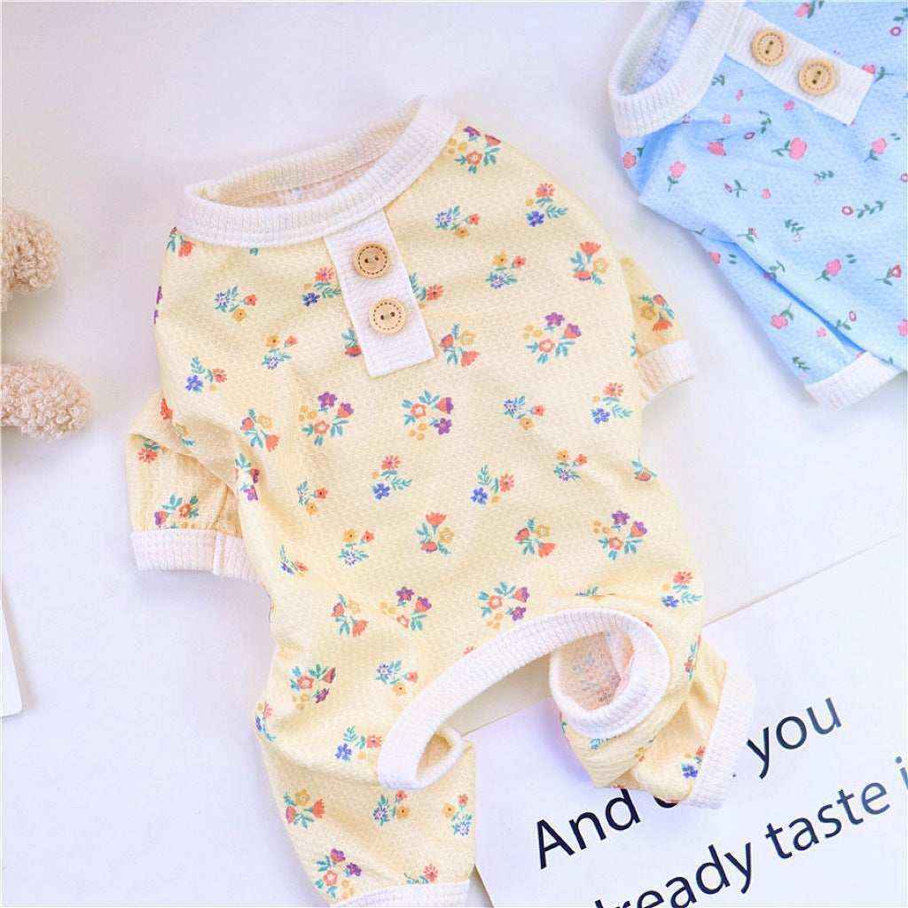 Yellow floral baby onesie with wooden buttons and white trim on a white surface