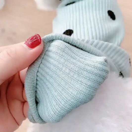 Hand holding soft, light blue ribbed fabric sleeve with black polka dots on a plush white stuffed toy