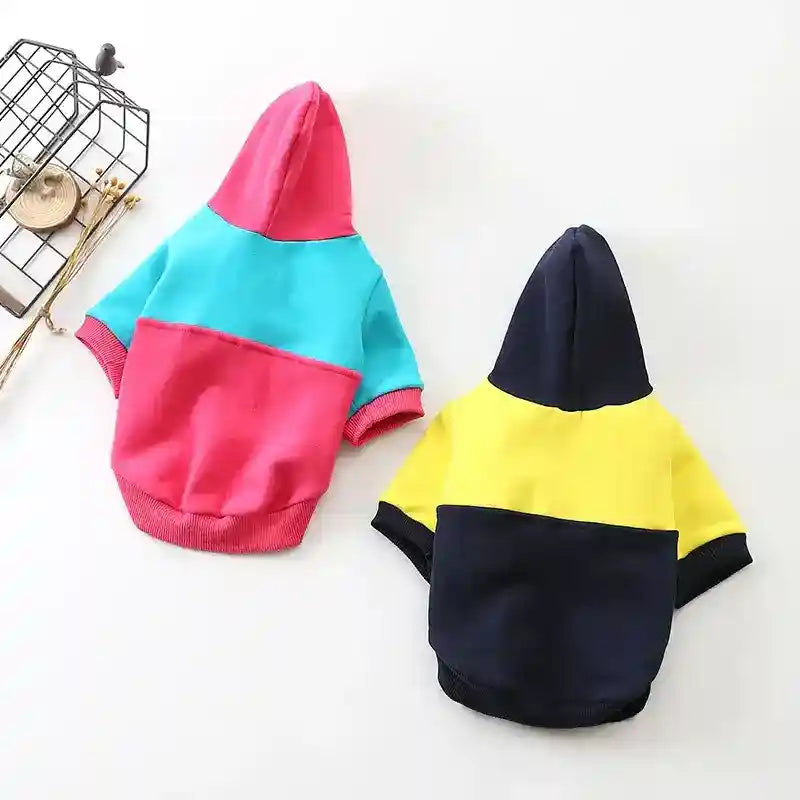 Two color-blocked hooded dog sweaters in pink-blue and yellow-black on white background
