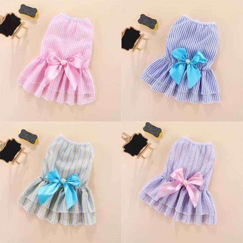 Four small striped dog dresses in pink, blue, yellow, and purple with large satin bows and pearl centers