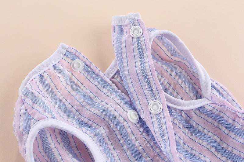 Close-up of pastel blue and pink striped baby vest with white snap buttons on beige background