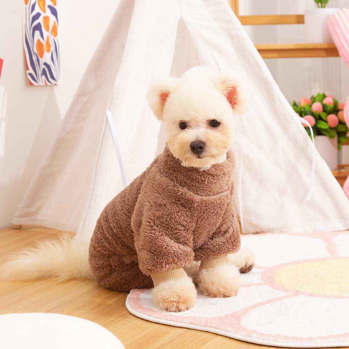 Small white dog wearing brown fluffy sweater sitting on flower rug near indoor teepee tent