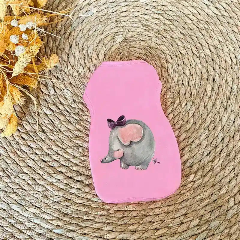 Pink baby onesie with cute cartoon elephant wearing a bow, placed on woven mat with dried flowers