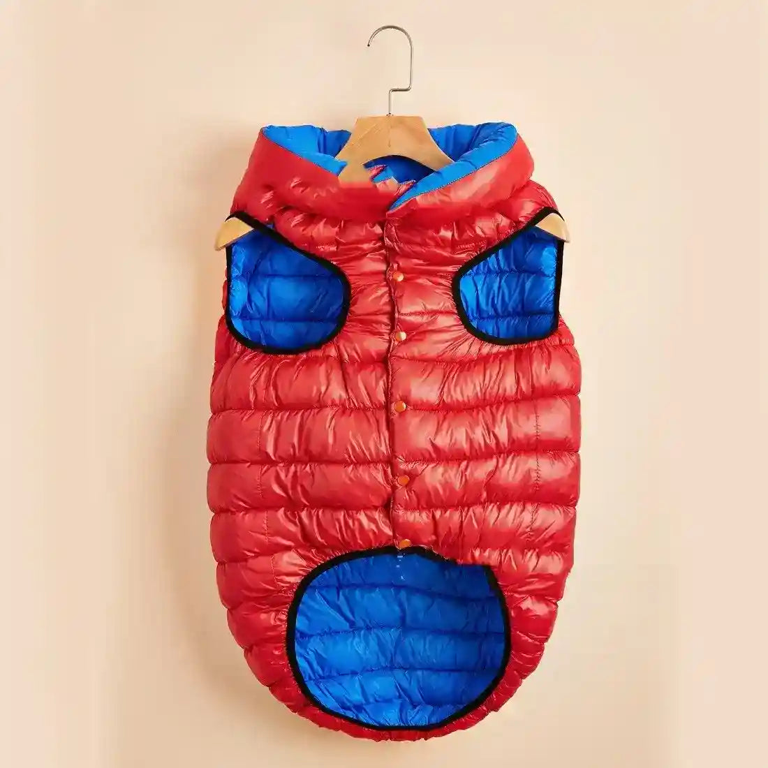 Red and blue padded dog jacket with hood hanging on wooden hanger