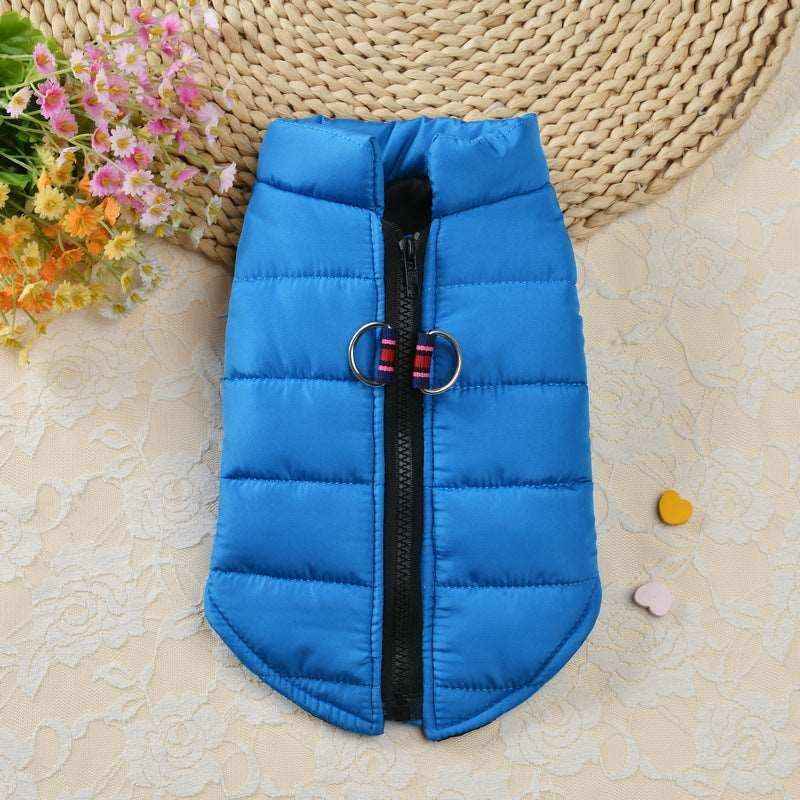 Blue padded dog vest with central zipper and dual metal rings, displayed on a floral mat with scattered flowers