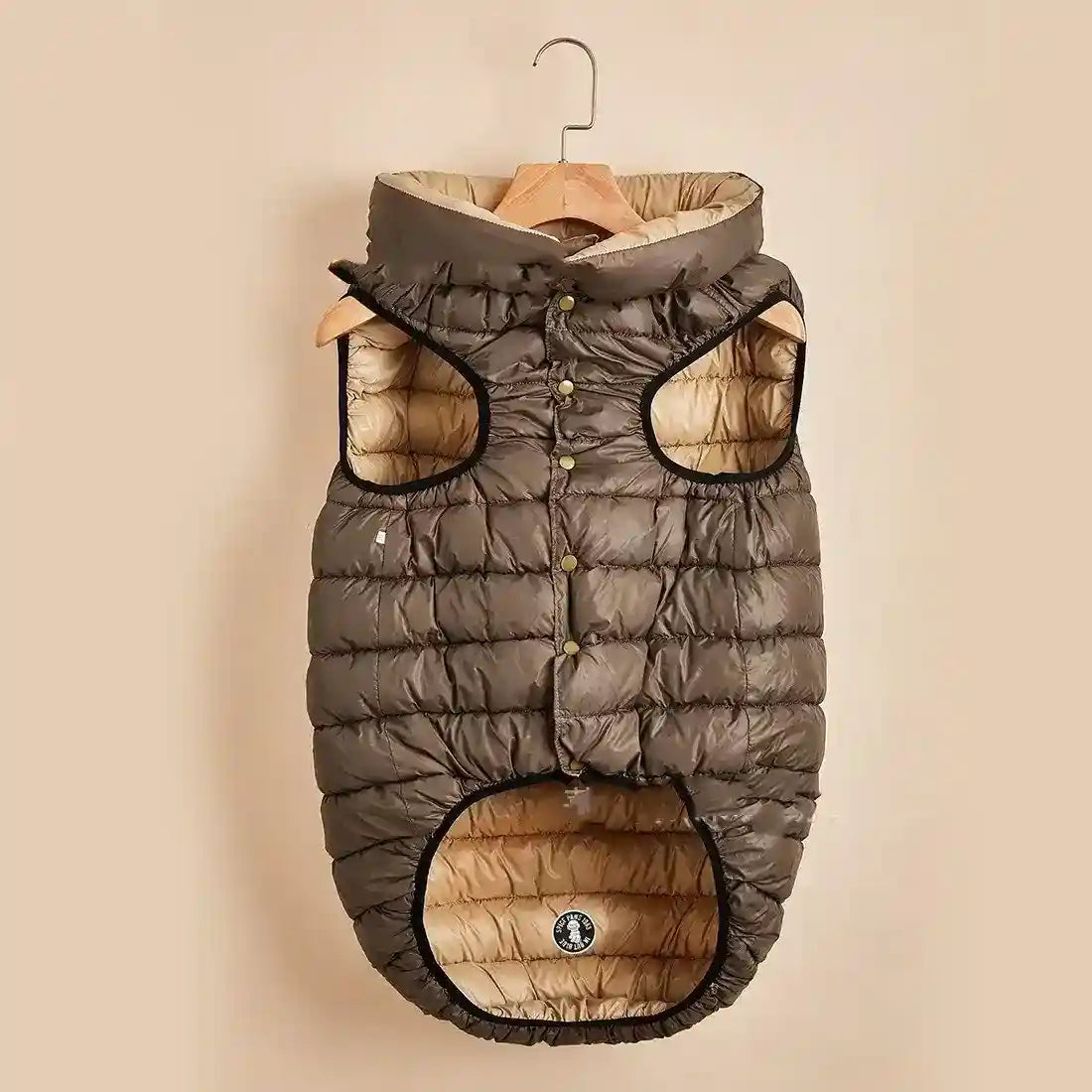 Brown and beige padded dog vest with hood hanging on wooden hanger, quilted pet jacket
