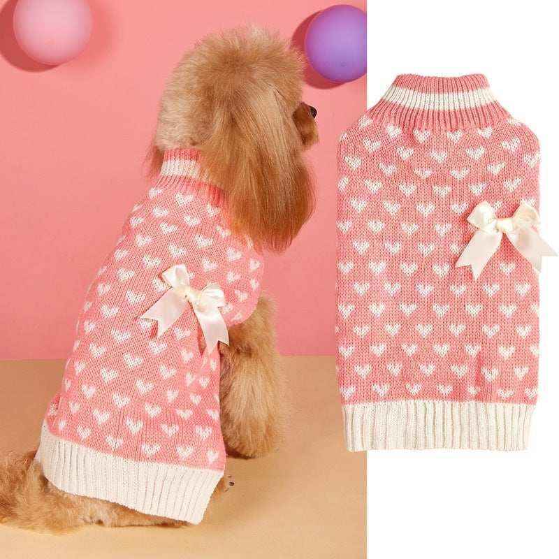 Small dog wearing pink knit sweater with white hearts and bow, displayed beside matching dog sweater