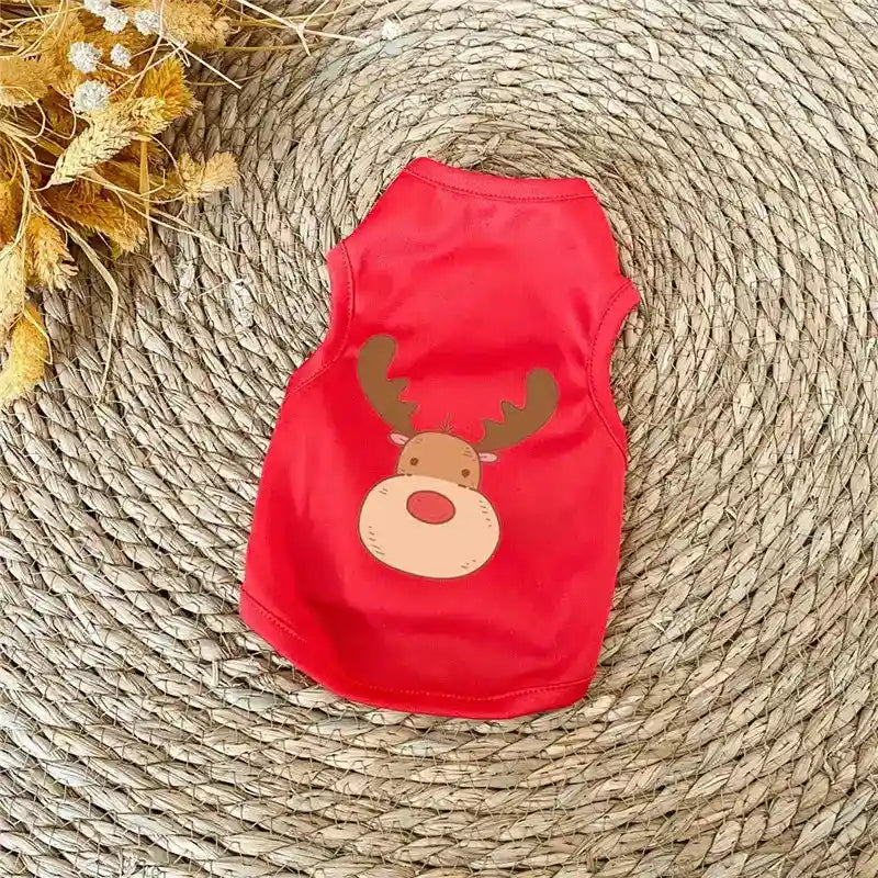 Red pet vest with cute cartoon reindeer print on woven natural fiber mat with dried flowers