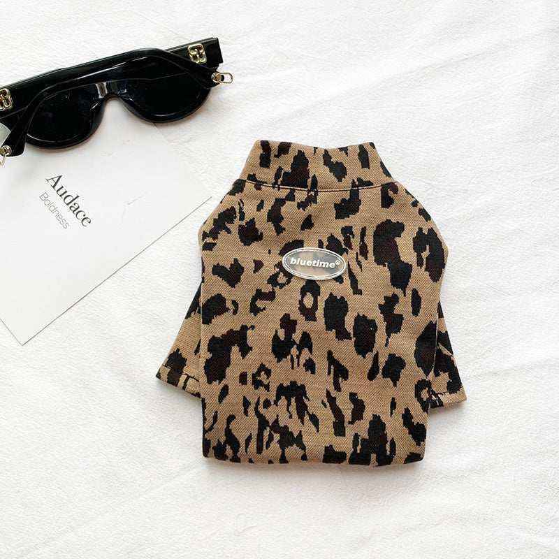 Leopard print pet sweater with blue time logo, black sunglasses and white card on white fabric background