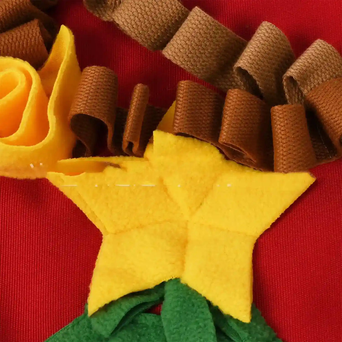Close-up of yellow fleece star and curled brown fabric strips on red textured background