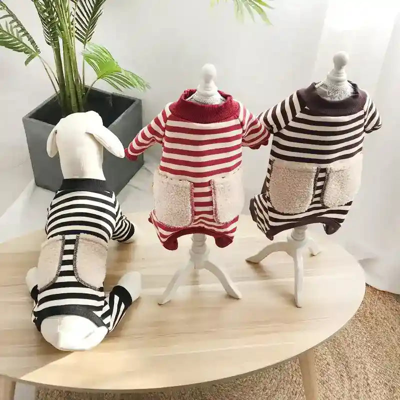 Three striped dog sweaters in black, red, and brown on mannequins and a dog model on a wooden table