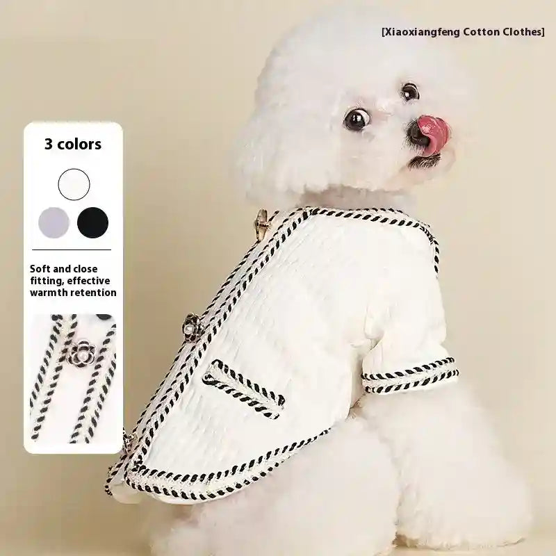 White poodle dog wearing soft, warm white cotton coat with black trim and decorative buttons