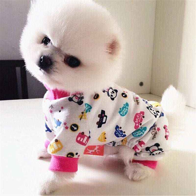 Small white fluffy dog wearing colorful panda print pet pajamas with pink cuffs