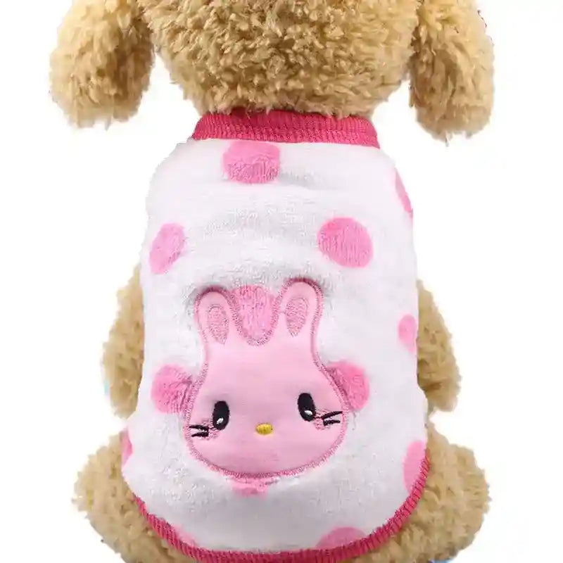 Fluffy beige dog wearing white and pink polka dot pet sweater with pink bunny face design