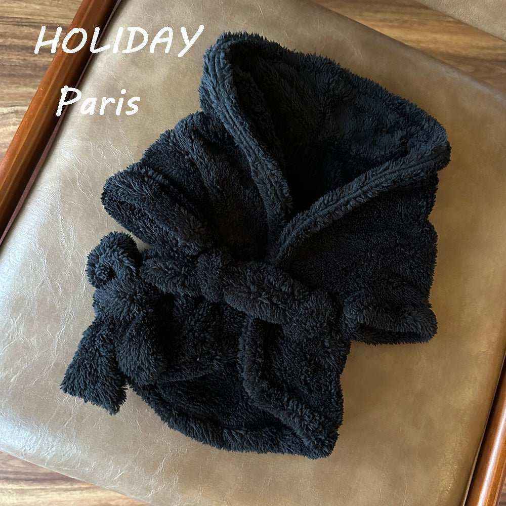 Black fluffy absorbent dog bathrobe with hood and belt on beige leather surface