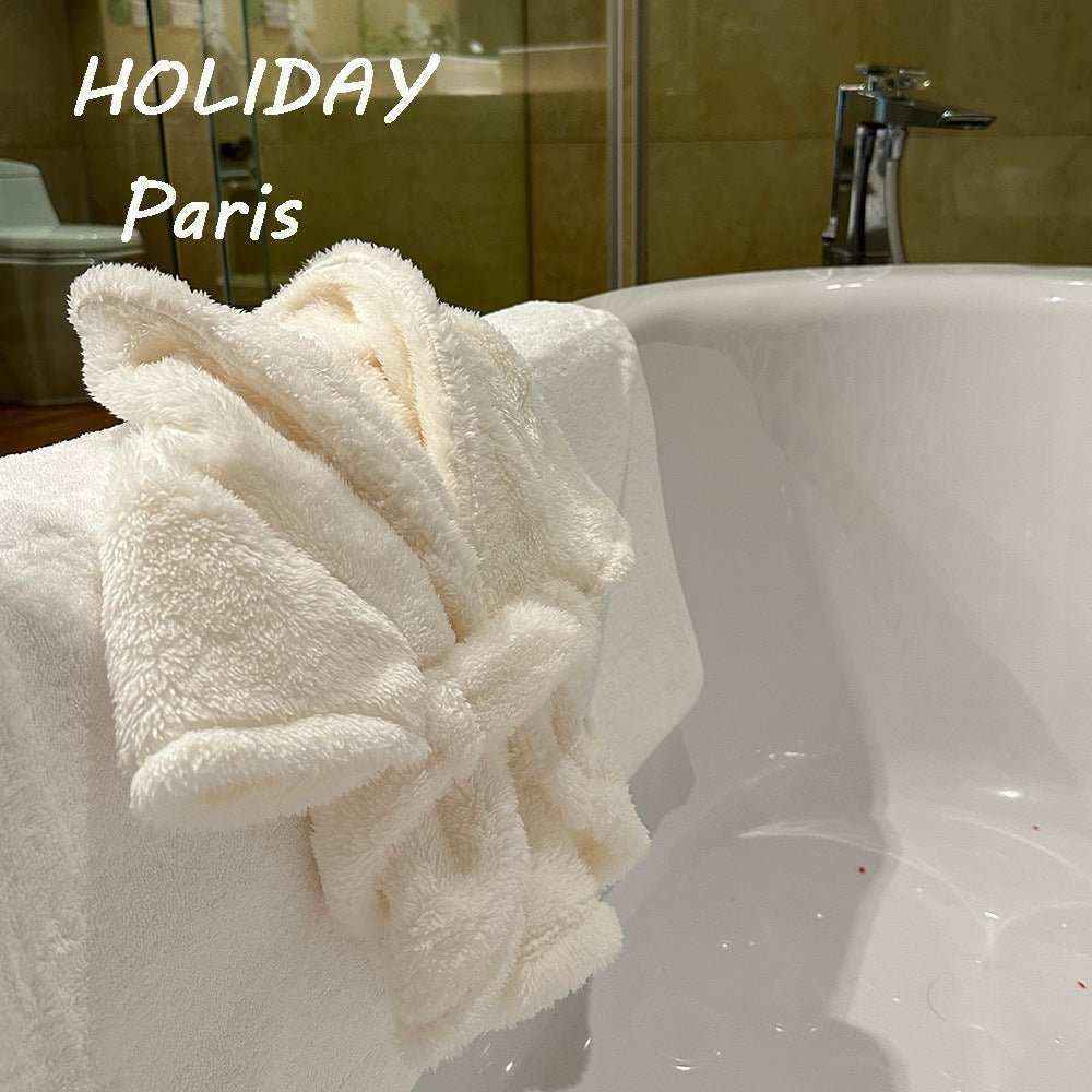 White fluffy bathrobe and towel on bathtub in modern bathroom with HOLIDAY Paris text