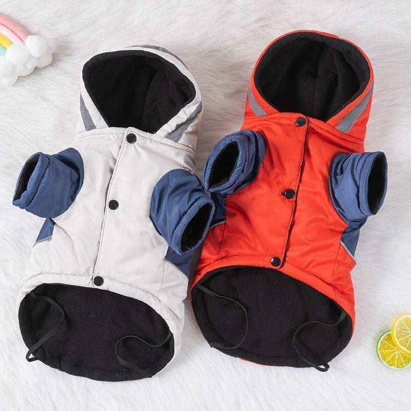 Two warm dog jackets in white and orange with blue sleeves and hoods on a soft white surface