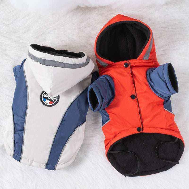 Two sporty dog jackets with hoods, one white and blue, the other red and blue, on a white surface