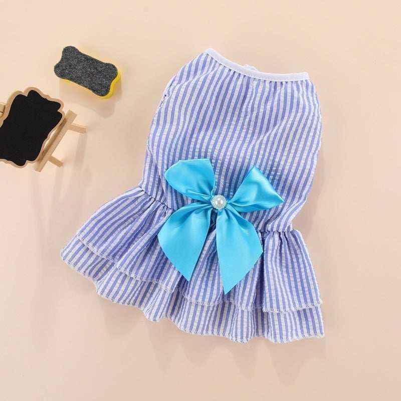 Blue and white striped pet dress with a large blue bow and pearl detail on beige background