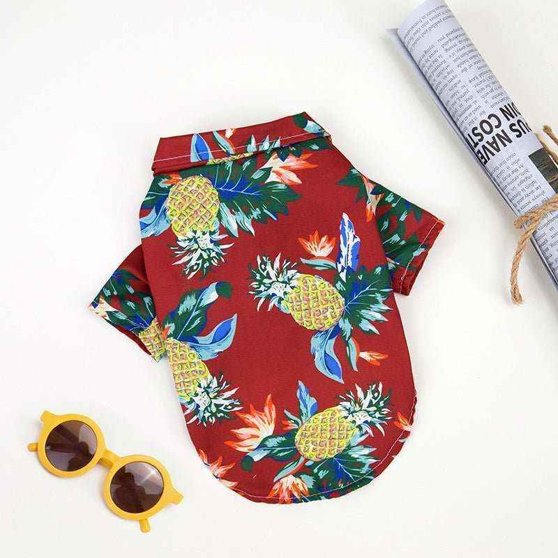 Red Hawaiian dog shirt with bright pineapple and tropical leaf print, paired with yellow sunglasses and rolled newspaper