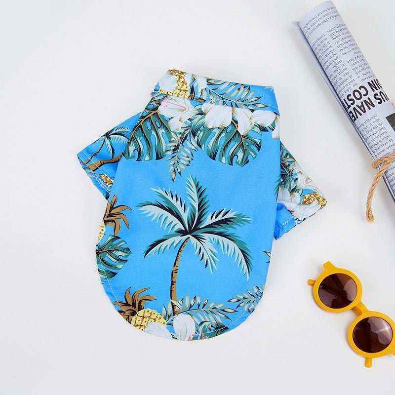 Hawaiian-style blue dog shirt with palm tree and tropical leaf print, yellow sunglasses and rolled newspaper
