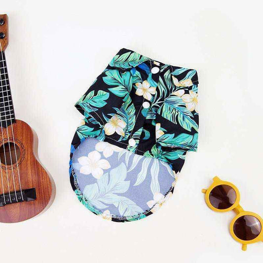 Hawaiian style dog shirt with tropical leaf and flower print, displayed with ukulele and yellow sunglasses