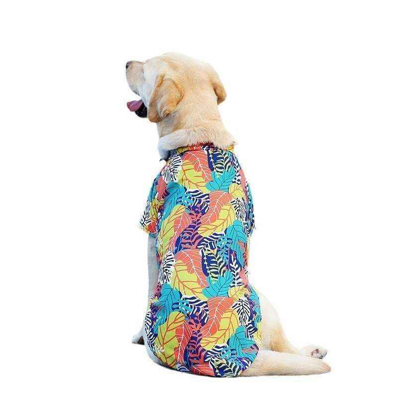 Yellow labrador dog wearing a colorful Hawaiian shirt with tropical leaf print sitting against white background